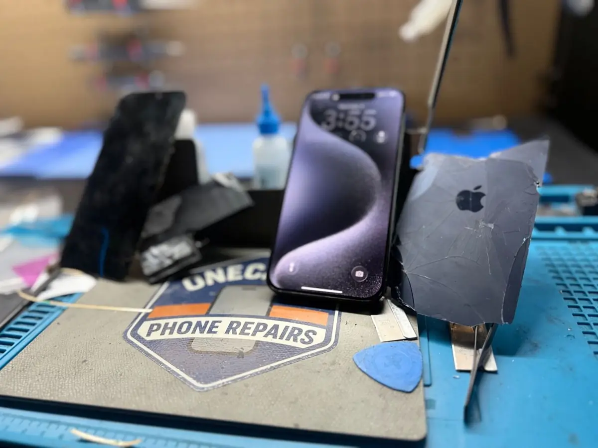 iPhone with a cracked screen on the repair bench at OneClick Phone Repairs in Fullerton, CA